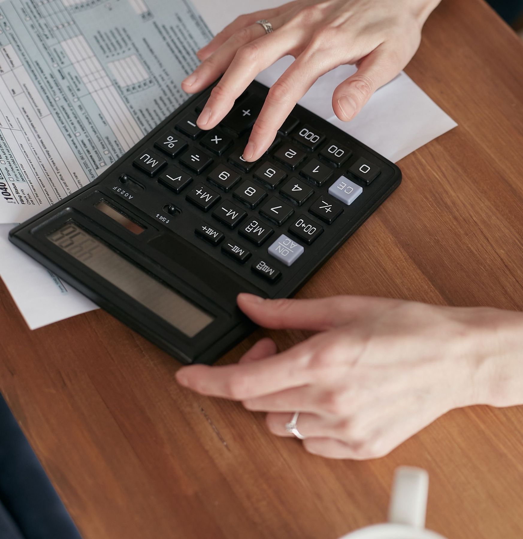 Hands using a calculator over payment documents